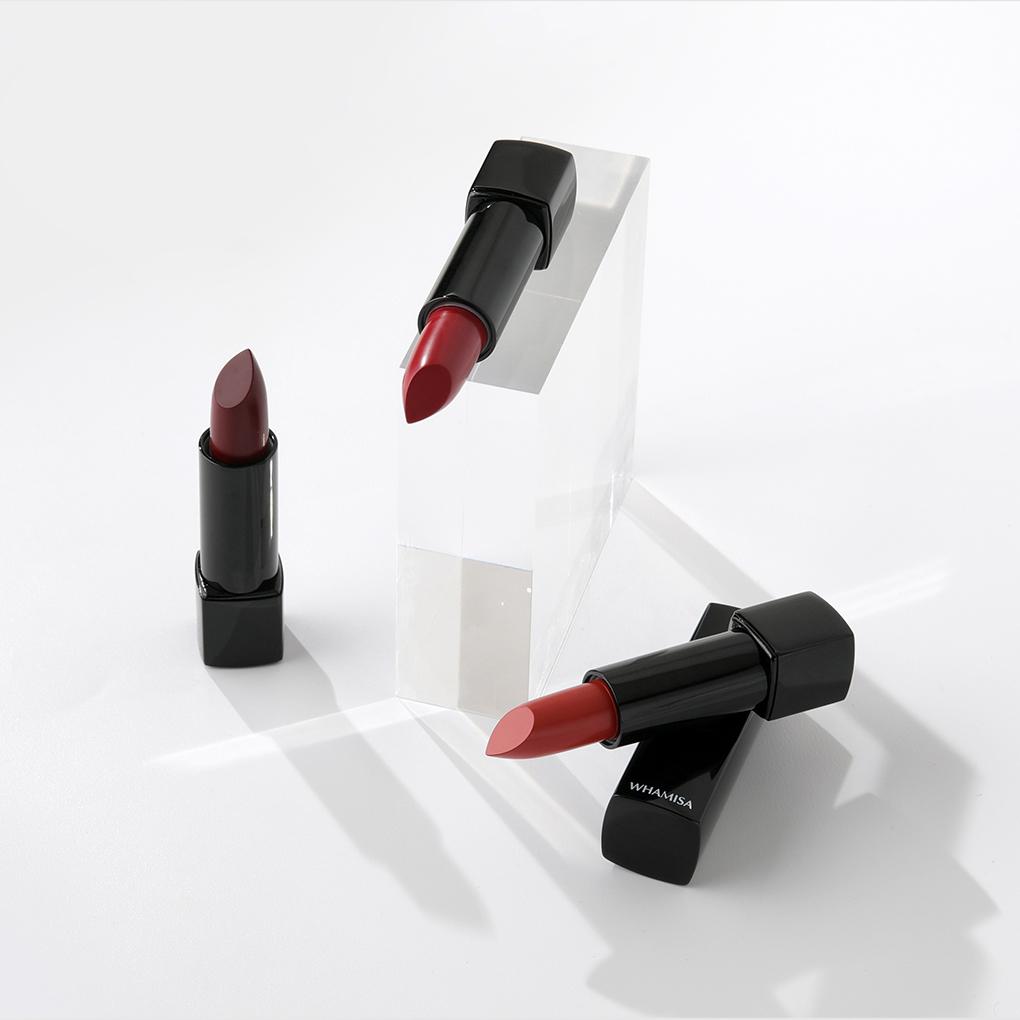 Whamisa Organic Flowers Lip Color in three different shades of red. Three products are arranged left to right: darkest red shade, middle tone red shade, and lightest red shade.
