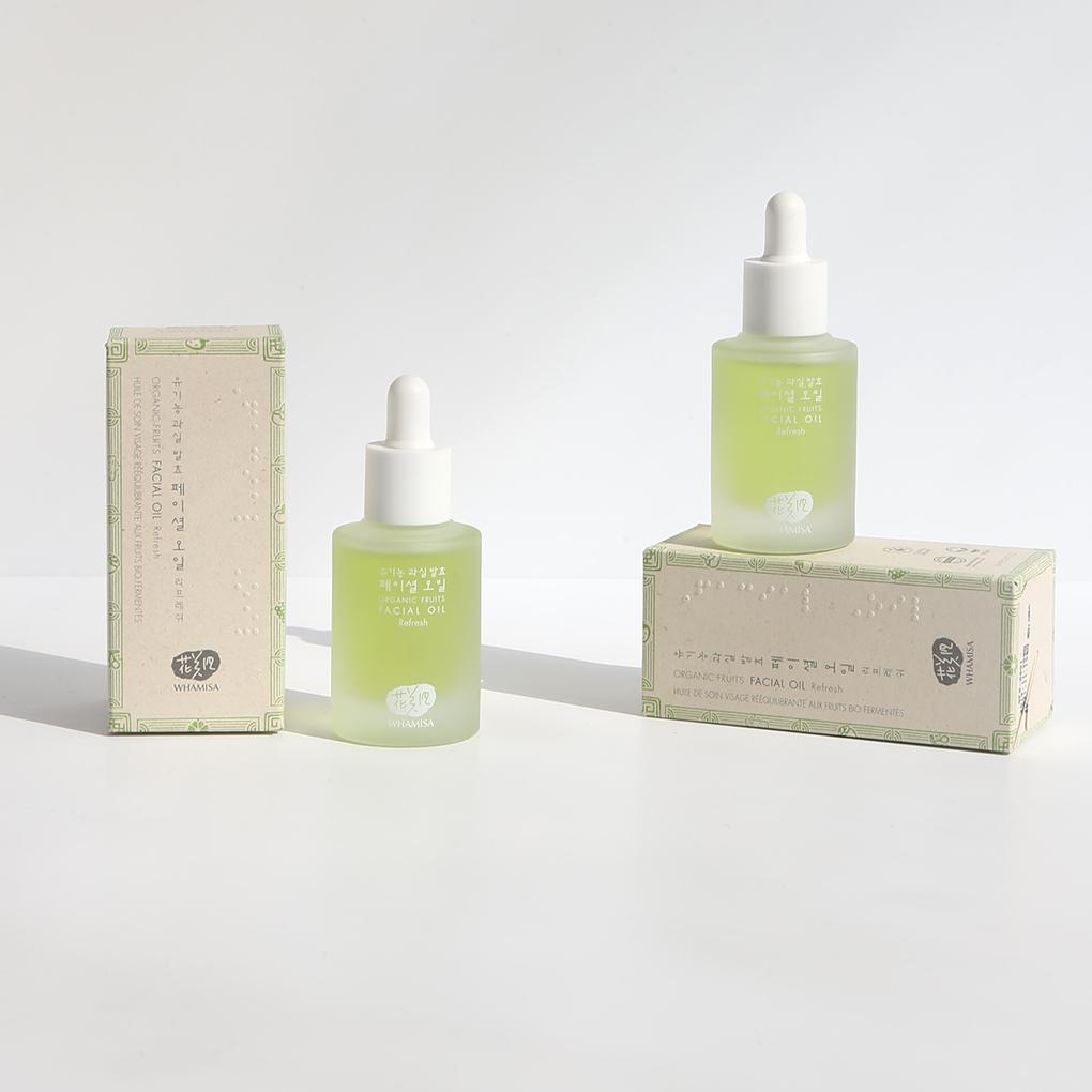Whamisa ﻿Organic Flowers Facial Oil Refresh bottled in a semi-transparent bottle with lime green content inside. The cap works as a dropper. Two bottles are arranged along with the two cardboard boxes which the product comes in.﻿